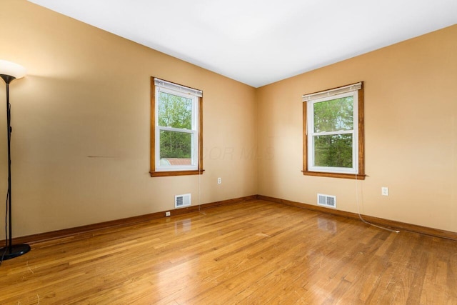 unfurnished room featuring baseboards, visible vents, and light wood-type flooring