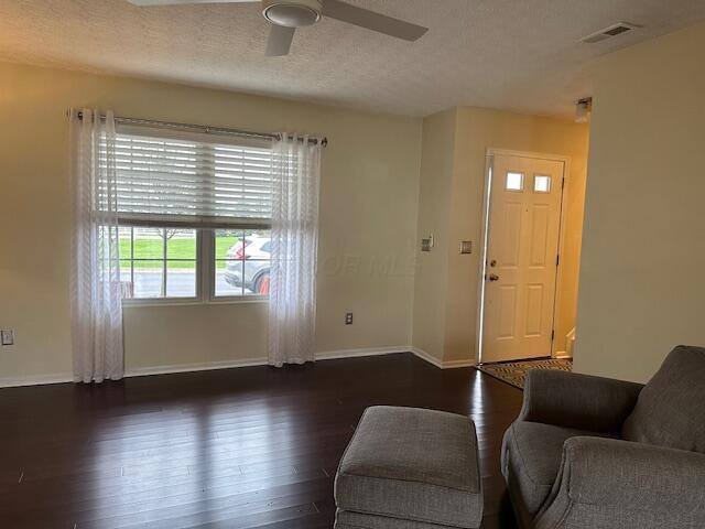 living room with wood finished floors, ceiling fan, baseboards, and visible vents