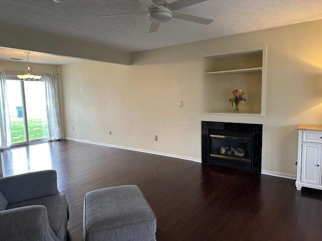 living room featuring a tile fireplace, baseboards, ceiling fan with notable chandelier, and dark wood finished floors