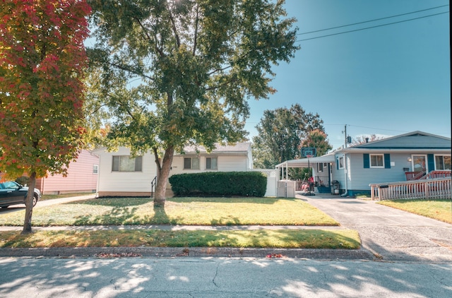 ranch-style home featuring a carport, a front lawn, fence, and driveway