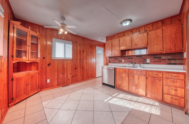 kitchen with light countertops, a ceiling fan, wood walls, dishwasher, and a sink
