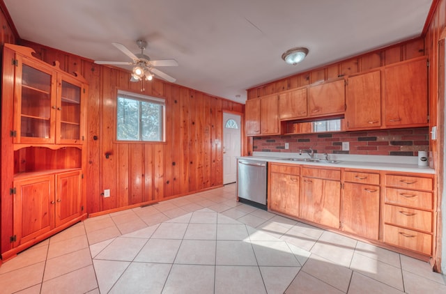 kitchen with a ceiling fan, wood walls, light countertops, dishwasher, and a sink