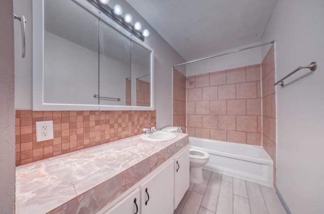 bathroom with backsplash, toilet, vanity, and shower / washtub combination