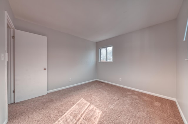 spare room with baseboards and carpet floors