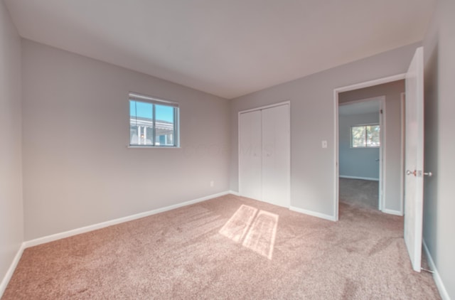 unfurnished bedroom with baseboards, multiple windows, and carpet flooring