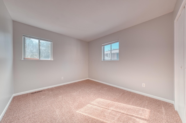 carpeted spare room with visible vents and baseboards