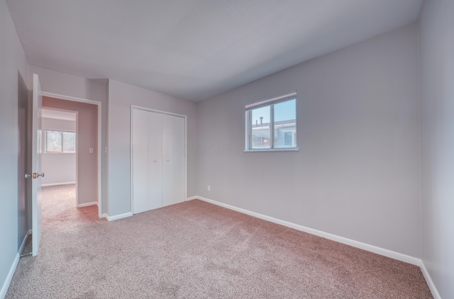 unfurnished bedroom featuring a closet, multiple windows, baseboards, and carpet floors