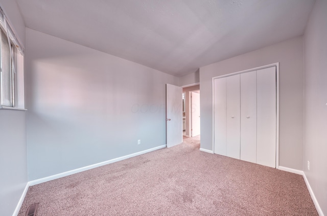 unfurnished bedroom with a closet, visible vents, baseboards, and carpet