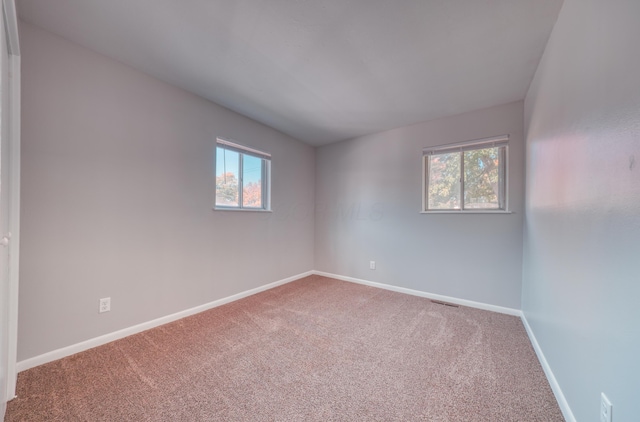 unfurnished room with carpet flooring, baseboards, and visible vents