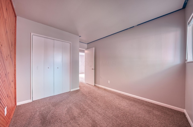 unfurnished bedroom with a closet, baseboards, and carpet