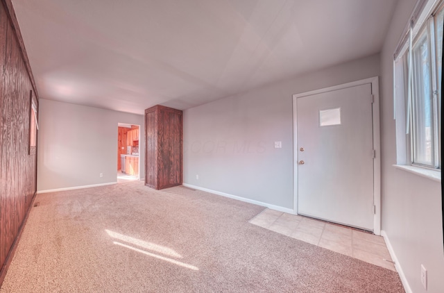 spare room featuring light colored carpet and baseboards