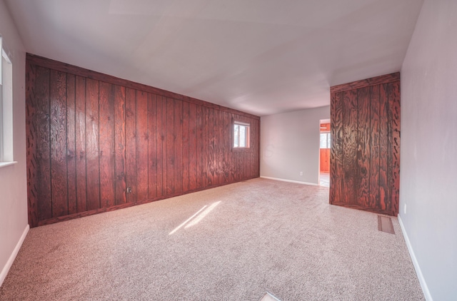 spare room featuring wooden walls, baseboards, and carpet floors