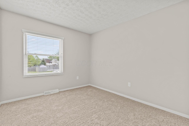 carpeted spare room with a textured ceiling, visible vents, and baseboards