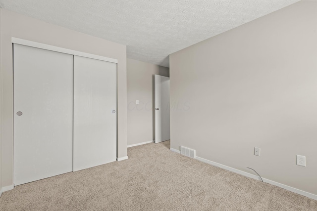 unfurnished bedroom with carpet flooring, a closet, visible vents, and baseboards