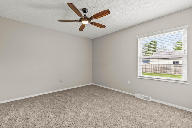 carpeted spare room with a textured ceiling, visible vents, baseboards, and a ceiling fan
