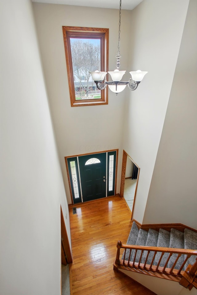 entryway with a chandelier, wood finished floors, baseboards, and stairway