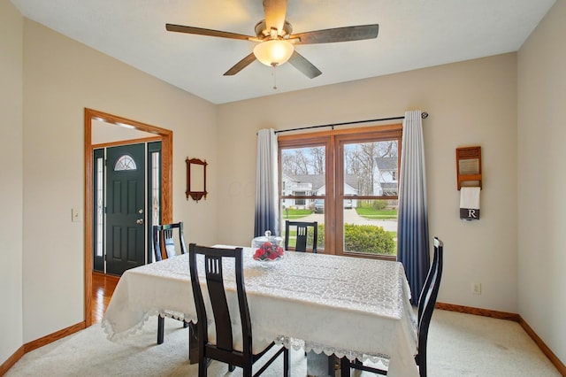 dining area with baseboards, a ceiling fan, and light colored carpet