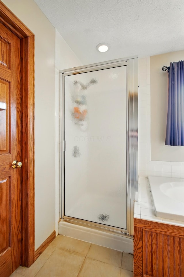 full bathroom featuring a textured ceiling, tile patterned flooring, and a shower stall