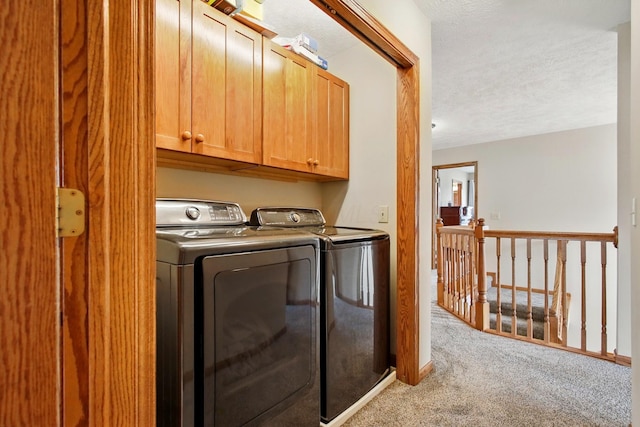 laundry area with cabinet space, independent washer and dryer, light carpet, and a textured ceiling