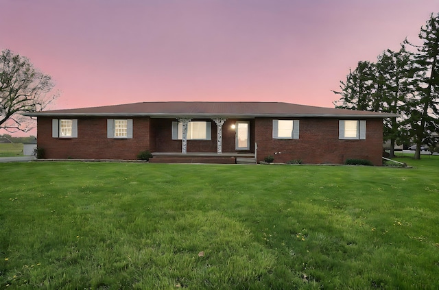 ranch-style home with covered porch, a front yard, and brick siding