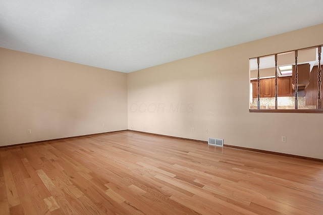 spare room with visible vents, baseboards, and light wood-style flooring