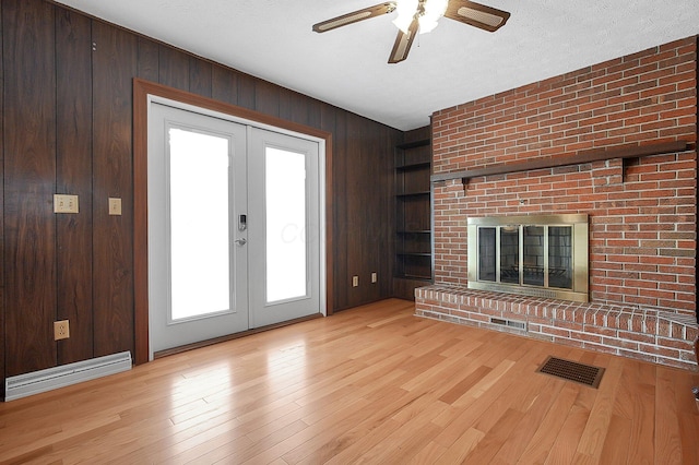 unfurnished living room featuring french doors, wood walls, visible vents, and built in features