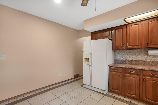 kitchen featuring tasteful backsplash, light tile patterned floors, a ceiling fan, dark countertops, and white refrigerator with ice dispenser