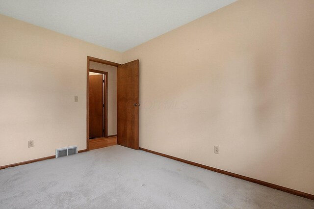 empty room with carpet, visible vents, and baseboards