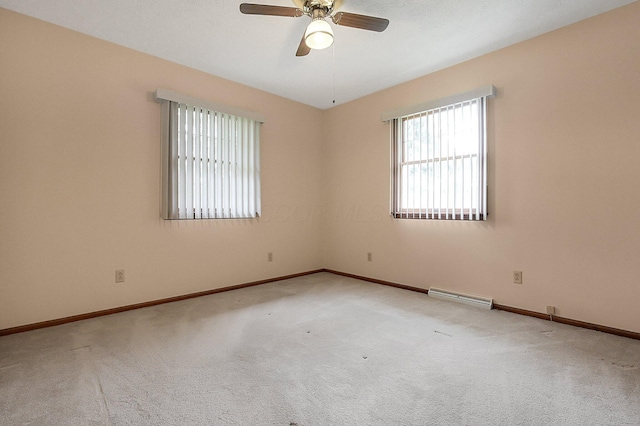 carpeted empty room with ceiling fan and baseboards