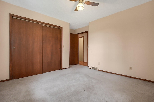unfurnished bedroom with a closet, visible vents, light colored carpet, and baseboards