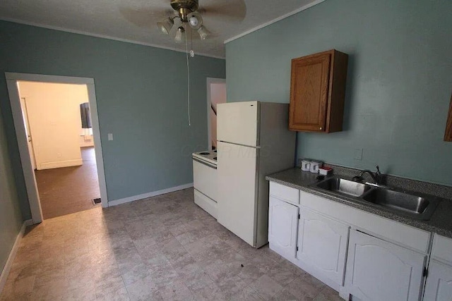 kitchen with a sink, dark countertops, a ceiling fan, white appliances, and crown molding
