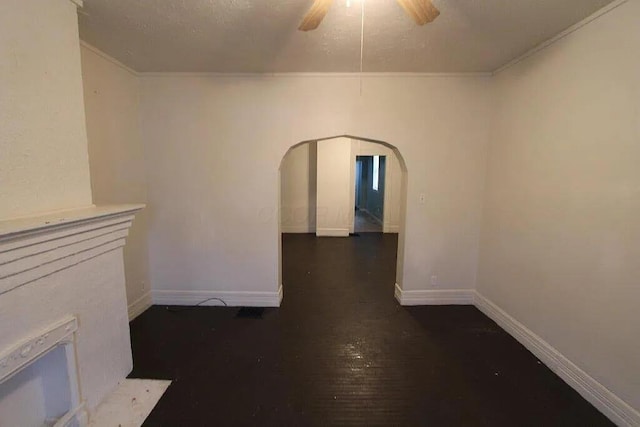 empty room with baseboards, arched walkways, ornamental molding, a ceiling fan, and wood finished floors