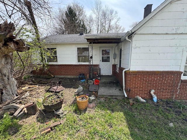 6927 Rings Rd, Dublin, OH 43016 - property entrance featuring brick siding, a chimney, and a shingled roof