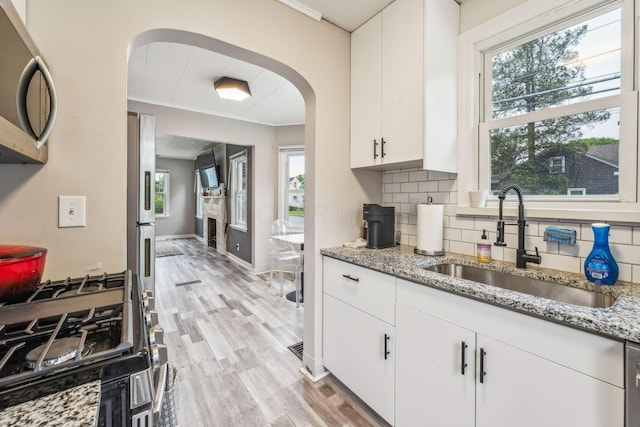 1329 Studer Ave, Columbus, OH 43206 - kitchen with appliances with stainless steel finishes, arched walkways, light wood-style floors, decorative backsplash, and light stone counters