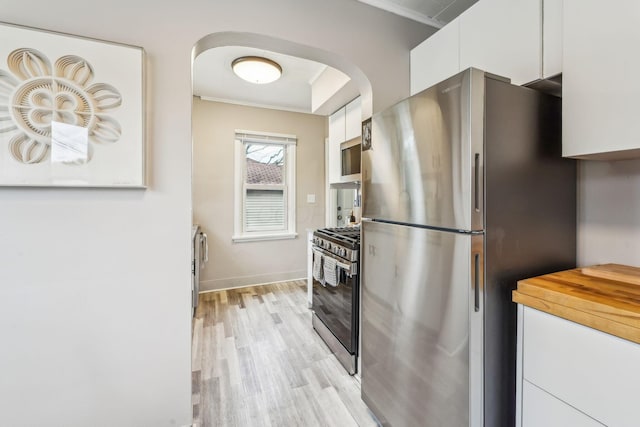 1329 Studer Ave, Columbus, OH 43206 - kitchen with stainless steel appliances, white cabinets, arched walkways, light wood-style floors, and ornamental molding