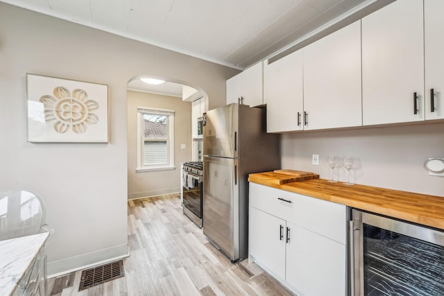 1329 Studer Ave, Columbus, OH 43206 - kitchen with stainless steel appliances, beverage cooler, butcher block countertops, arched walkways, and light wood finished floors