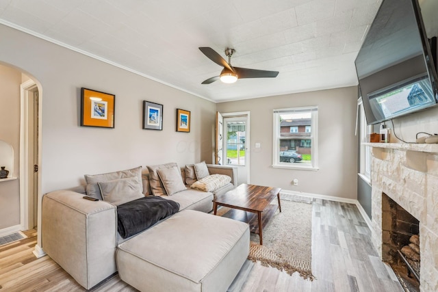 1329 Studer Ave, Columbus, OH 43206 - living room with arched walkways, a ceiling fan, light wood finished floors, a fireplace, and ornamental molding