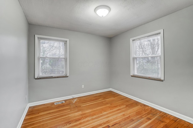 empty room with visible vents, plenty of natural light, and baseboards