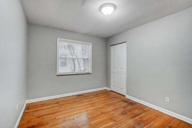 spare room with light wood-style floors, visible vents, and baseboards