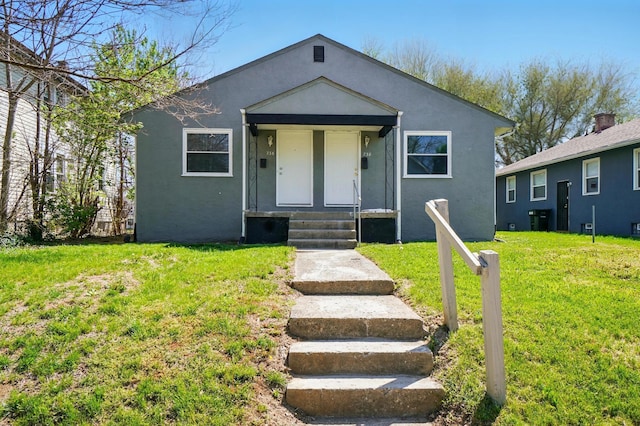 bungalow-style house featuring a front yard, entry steps, and stucco siding