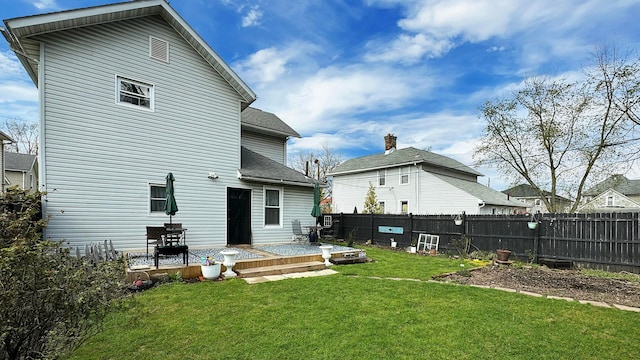 back of property with a fenced backyard, a lawn, and roof with shingles