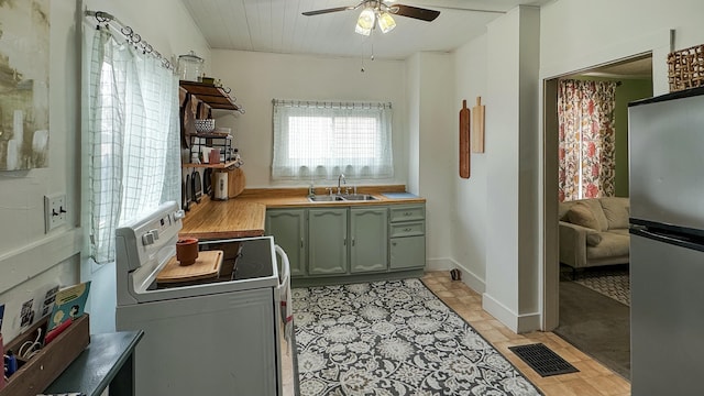kitchen with freestanding refrigerator, white range with electric cooktop, visible vents, a sink, and green cabinetry