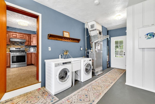 clothes washing area featuring a textured ceiling, laundry area, heating unit, and washing machine and dryer