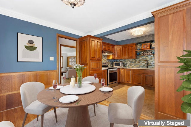 dining area featuring light wood-style floors, a wainscoted wall, and wooden walls