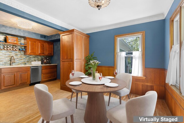 dining area with visible vents, crown molding, wainscoting, indoor wet bar, and light wood finished floors