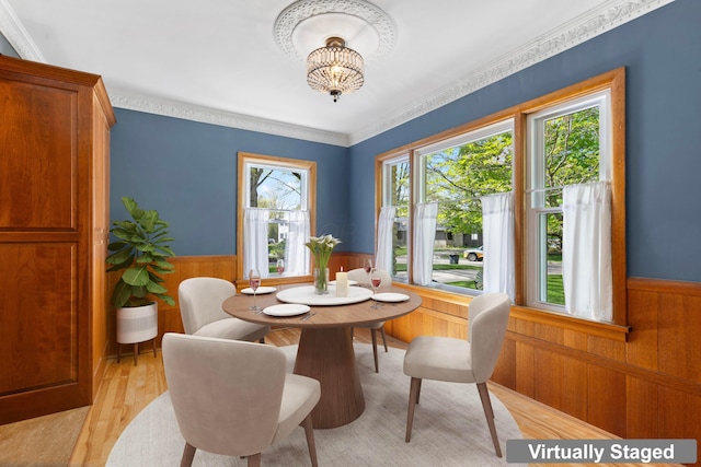 dining room with wooden walls, a notable chandelier, light wood finished floors, and a wainscoted wall