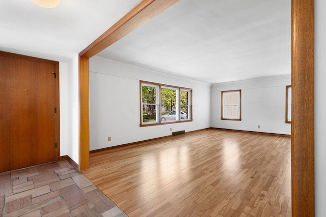 interior space featuring visible vents, ornamental molding, baseboards, and light wood-style flooring