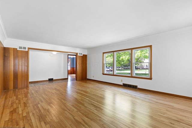 unfurnished living room with visible vents, ornamental molding, light wood finished floors, and baseboards