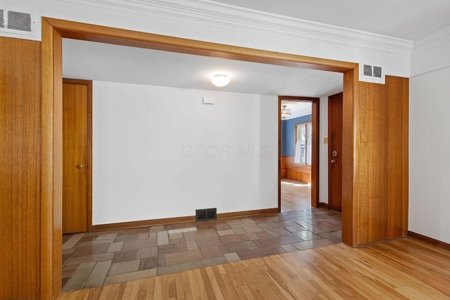 empty room featuring baseboards, wood finished floors, and visible vents