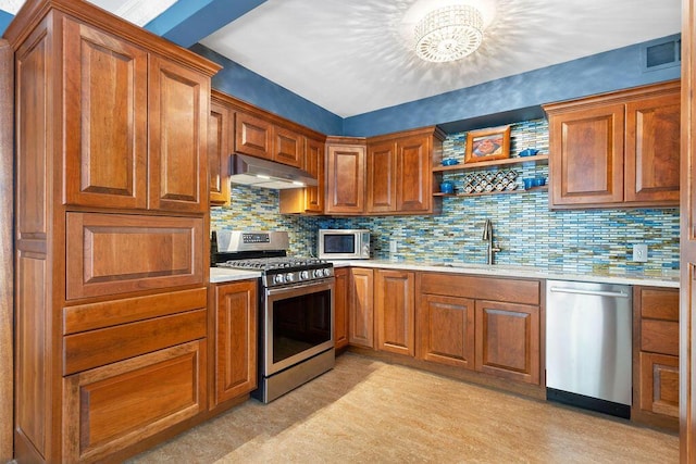 kitchen featuring a sink, light countertops, brown cabinetry, stainless steel appliances, and under cabinet range hood